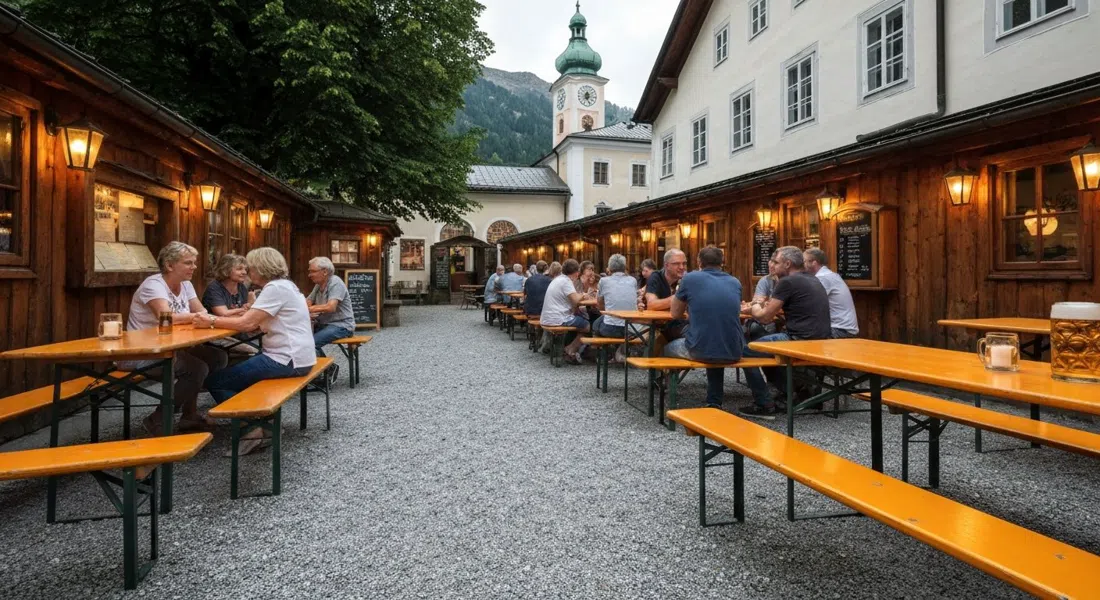 Augustiner Braugasthof Krimpelstätter的灯笼照亮的栗树啤酒花园,脚下是砾石,长桌上放着一杯新鲜的玛尔茨啤酒